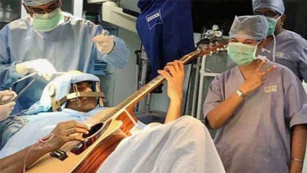 Indian man Mr Prasad plays guitar during surgery. 